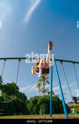 Une adolescente balançant haut dans les équipements de terrain de jeux pour enfants au domaine de Tauranga, en Nouvelle-Zélande. Banque D'Images