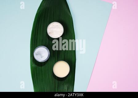 Le concept de création de cosmétiques naturels. Composition spa, crème et baumes dans un bol sur fond bleu et rose pastel. CopySpace, planéité. Banque D'Images