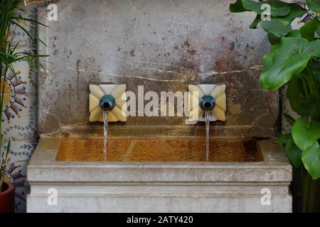 Fontaine en pierre avec deux tuyaux d'eau dans une cour intérieure Banque D'Images