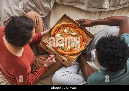Vue panoramique sur les jeunes couples assis sur le lit avec pizza et petit déjeuner le matin dans la chambre Banque D'Images