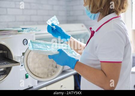 Infirmière féminine faisant la stérilisation des instruments médicaux dentaires en autoclave. Service de stérilisation à la clinique dentaire Banque D'Images