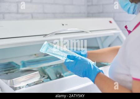 Infirmière féminine faisant la stérilisation des instruments médicaux dentaires en autoclave. Service de stérilisation à la clinique dentaire Banque D'Images