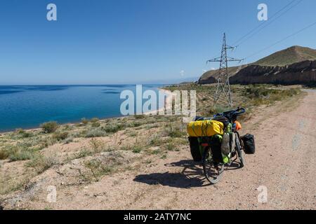 Le vélo du voyageur avec des sacs se trouve sur la route près du lac Issyk-Kul, paysage, Kirghizstan, vélo touristique Banque D'Images