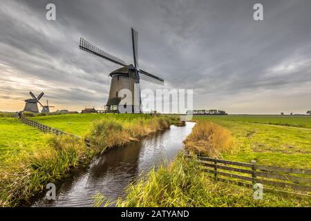 Moulin à vent traditionnel en bois le long du canal dans le vieux paysage agricole près de Schermerhorn, en Hollande du Nord. Pays-Bas Banque D'Images