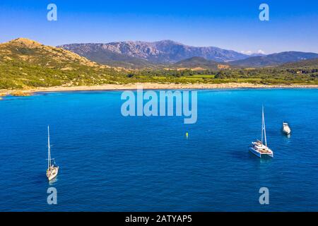 Voiliers amarré dans la baie naturelle avec plage sur la côte accidentée de la Corse, France Banque D'Images