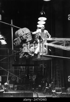 Le légendaire cinéaste WILLIAM H. DANIELS assis sur une grue à caméra sur la scène candiée avec l'équipage du film filmant DES ÂMES GRATTE-CIEL 1932 directeur Edgar Selwyn roman Faith Baldwin directeur de la photographie William H. Daniels direction artistique Cedric Gibbons Cosmopolitan Productions / Metro Goldwyn Mayer Banque D'Images