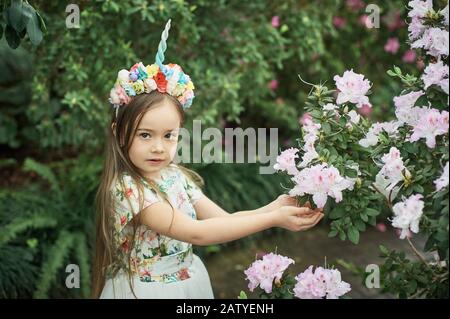 Fantasy Little girl avec corne de licorne arc-en-ciel avec fleurs dans le parc azalea. Pour Halloween Banque D'Images