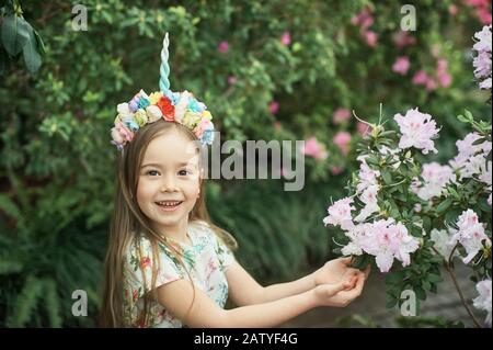 Fantasy Little girl avec corne de licorne arc-en-ciel avec fleurs dans le parc azalea. Pour Halloween Banque D'Images