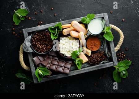 Dessert tiramisu. Ingrédients pour la préparation du tiramisu. Vue de dessus. Sur fond de pierre noire. Espace libre pour votre texte. Banque D'Images