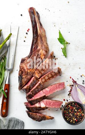 Steak grillé sur l'os tranché, herbes et épices sur fond de bois. Barbecue. Vue de dessus. Espace libre pour le texte. Banque D'Images