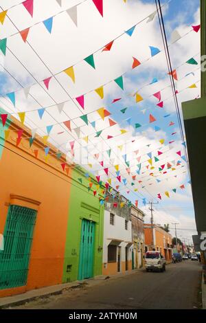 Pédicab (vélo taxi) dans une rue coloniale à Hunucma, Yucatan, Mexique. Les drapeaux de Papel Picado volent en hauteur. Banque D'Images