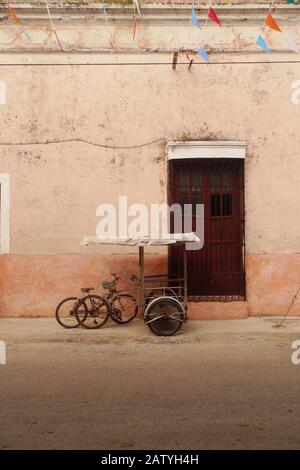 Pédicab (vélo taxi) dans une rue coloniale à Hunucma, Yucatan, Mexique. Les drapeaux de Papel Picado volent en hauteur. Banque D'Images