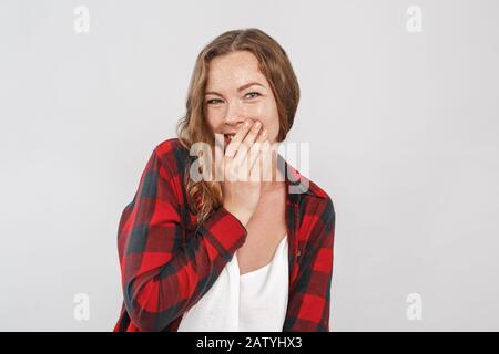 Freestyle. Jeune femme avec des cornichons debout isolé sur gris giggling joyeuse couvrant visage timide Banque D'Images