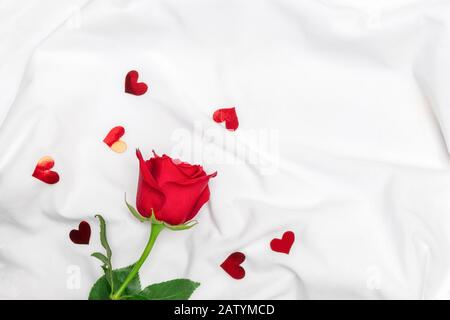 Au-dessus de la vue de rose rouge avec des coeurs brillants sur des draps blancs. Image avec espace de copie, plat. Banque D'Images