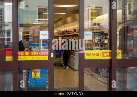 En regardant par les portes d'un supermarché, une femme achète des produits d'une allée de nourriture gelée Banque D'Images