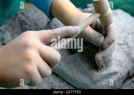 Enfant jouant à des jeux d'excavation de fossiles, de minéraux et de trésors. L'enfant utilise des outils, tels qu'un marteau. Banque D'Images