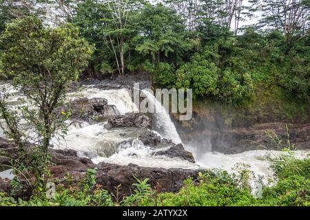 Hilo, Hawaï, États-Unis. - 14 janvier 2020: L'eau blanche tombe sur les rochers de lave à la lisière des chutes Rainbow. Végétation verte. Banque D'Images