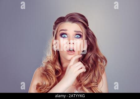 Des nouvelles choquantes. Belle choquée surprise gentiment blonde fille avec de grands yeux avec mois ouvert regardant l'appareil photo isolé sur un gris mauve backgroun Banque D'Images