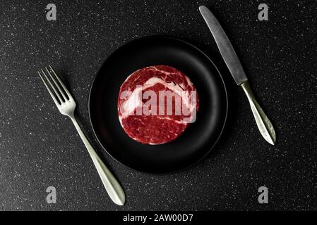 Viande de bœuf de bœuf de qualité brute, viande de bœuf aux yeux, steak sur fond de pierre noire. Banque D'Images