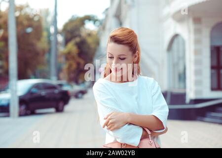 Portrait de belle fille debout avec les bras repliés vers le bas. Arrière-plan isolé de la rue de la ville Banque D'Images