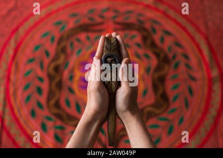 Un homme tient un tuyau Noya Rao en bois avec le tabac sacré Mapacho, des outils pour la cérémonie de Shaman en phytothérapie, sur une broderie cérémonielle Shipibo. Banque D'Images