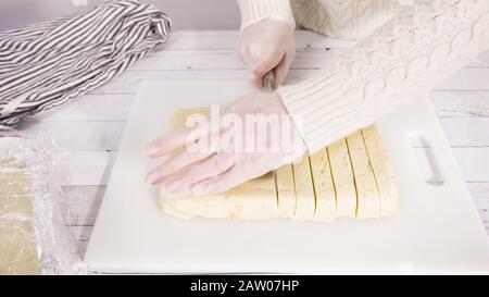 Étape par étape. Coupe de fudge de canne à sucre fait maison sur un tableau de découpe blanc. Banque D'Images