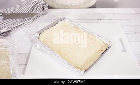 Étape par étape. Coupe de fudge de canne à sucre fait maison sur un tableau de découpe blanc. Banque D'Images