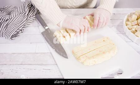 Étape par étape. Coupe de fudge de canne à sucre fait maison sur un tableau de découpe blanc. Banque D'Images