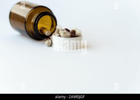 Médicaments et pilules. Médicaments sur fond blanc gros plan. Seau en verre brun avec capsules à l'intérieur sur un fond blanc. Pilules qui ont renversé Banque D'Images