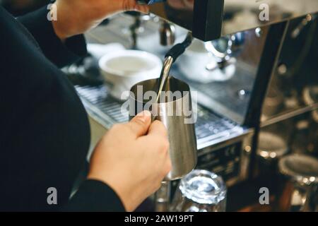 Close-up d'un barista la préparation de lait dans une machine à café pour l'ajout de café. Banque D'Images