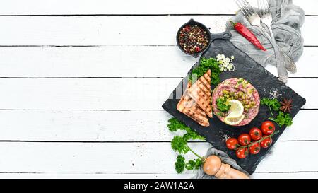 Tartare de boeuf avec jaune d'oeuf cru, avocat, câpres et oignons. Cuisine française. Vue de dessus. Espace libre pour votre texte. Banque D'Images