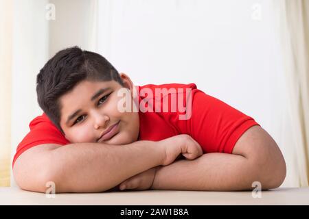 Portrait d'un garçon de chubby allongé sur la table. (Obésité) Banque D'Images