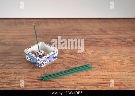 Composition minimaliste soignée avec des bâtonnets d'encens japonais sur table en bois et un bâton brûle dans le stand décoratif traditionnel. Banque D'Images