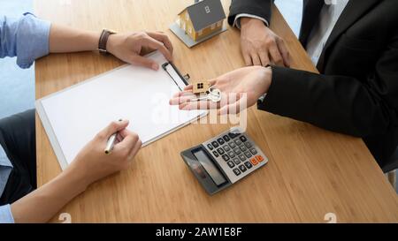 Vue de dessus de l'agent immobilier donnant la clé de maison à son client lors de la signature de l'accord de prêt à domicile Banque D'Images