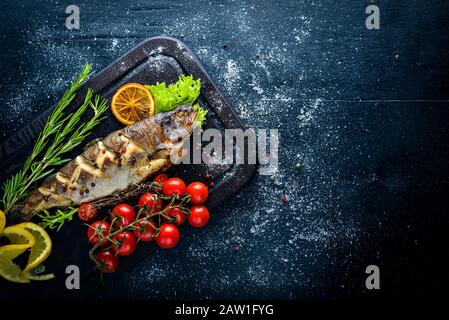 Poisson à la truite cuit aux herbes aromatiques et aux épices. Sur fond en bois. Banque D'Images