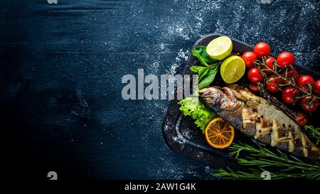 Poisson à la truite cuit aux herbes aromatiques et aux épices. Sur fond en bois. Banque D'Images