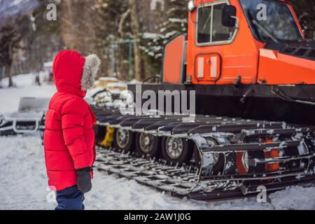 Un garçon regarde un chat de neige dans une station de ski Banque D'Images