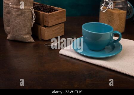 Une tasse vide de sachets de café et de jute, des récipients en bois remplis de fèves de cofée sur le fond de rouille. Sucre de canne. Banque D'Images