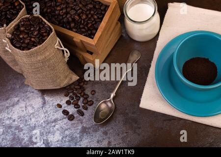 Tasse de sachets de café et de jute, récipients en bois remplis de fèves de cofée sur le fond de rouille. Sucre de canne. Faible luminosité. Banque D'Images