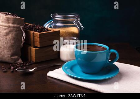 Tasse de sachets de café et de jute, récipients en bois remplis de fèves de cofée sur le fond de rouille. Sucre de canne. Faible luminosité. Banque D'Images