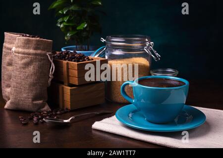 Tasse de sachets de café et de jute, récipients en bois remplis de fèves de cofée sur le fond de rouille. Sucre de canne. Faible luminosité. Banque D'Images