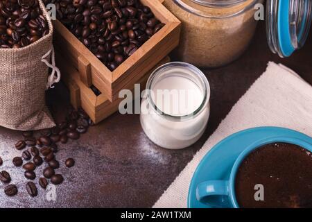 Tasse de sachets de café et de jute, récipients en bois remplis de fèves de cofée sur le fond de rouille. Sucre de canne. Faible luminosité. Banque D'Images