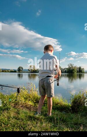 Pêche de garçon sur un lac. Magnifique étang à poissons près de Badin, Banska Bystrica, Slovaquie. Lieu de pêche. Soleil brillant sur l'étang de poissons en été. Banque D'Images