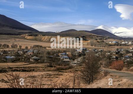 Vue de la route à un village de haute montagne près d'une colline tachetée recouverte de sable et de petites pierres d'une carrière abandonnée en Arménie Banque D'Images