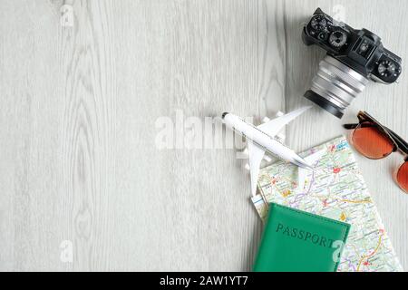 Accessoires pour voyageurs sur table en bois. Vue de dessus appareil photo vintage, modèle d'avion, carte, document de passeport, lunettes de soleil. Concept de planification des voyages. Voyage à tou Banque D'Images