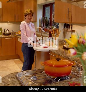 Femme cuisine dans une cuisine bien éclairée Banque D'Images