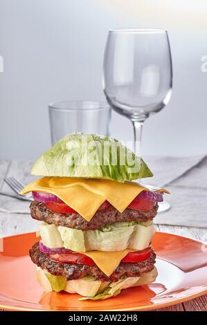 hamburger sans pain sur la laitue, sans gluten, avec légumes, viandes de boeuf et fromage. sur fond de bois. à côté des verres en verre. Banque D'Images