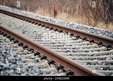 Gros plan d'une ligne de chemin de fer légèrement rouillée avec des traverses de chemin de fer en béton sur un ballast de voie en pierre concassée dans un environnement naturel. Vu à Germ Banque D'Images