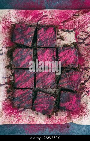 Chocolat noir fait maison Beetroot Brownies surmontés de ganache d'huile de coco au chocolat et de poudre de betterave Banque D'Images
