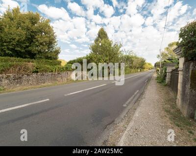 France route locale traversant une petite ville entourée de maisons et de végétation Banque D'Images